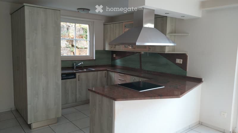 Modern kitchen with wooden cabinets, stainless steel appliances, and a central island with a dark countertop.