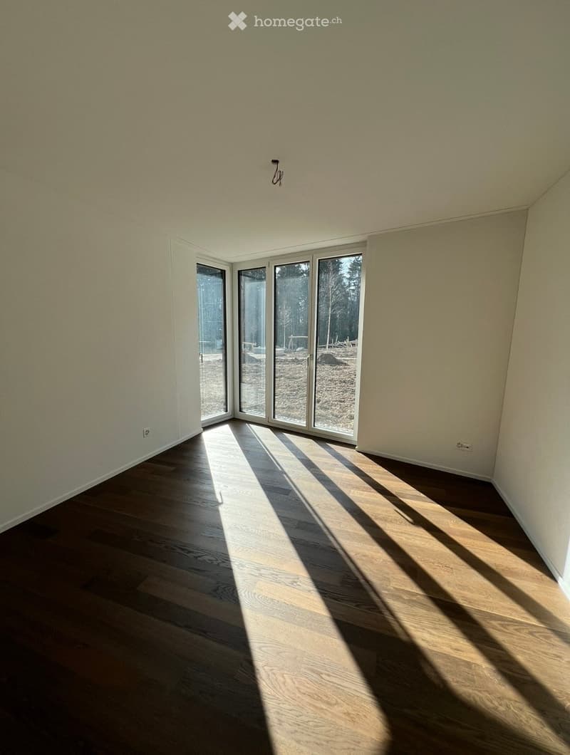 Empty room with wooden flooring and large sliding glass doors leading to an outdoor area.
