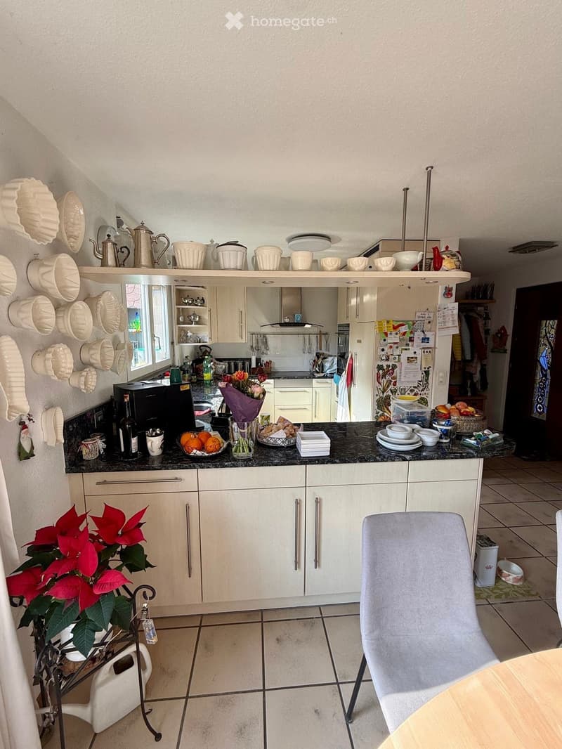 kitchen with white cabinets, black granite countertop, white plates, flowers, coffee machine, refrigerator, dining table, chair