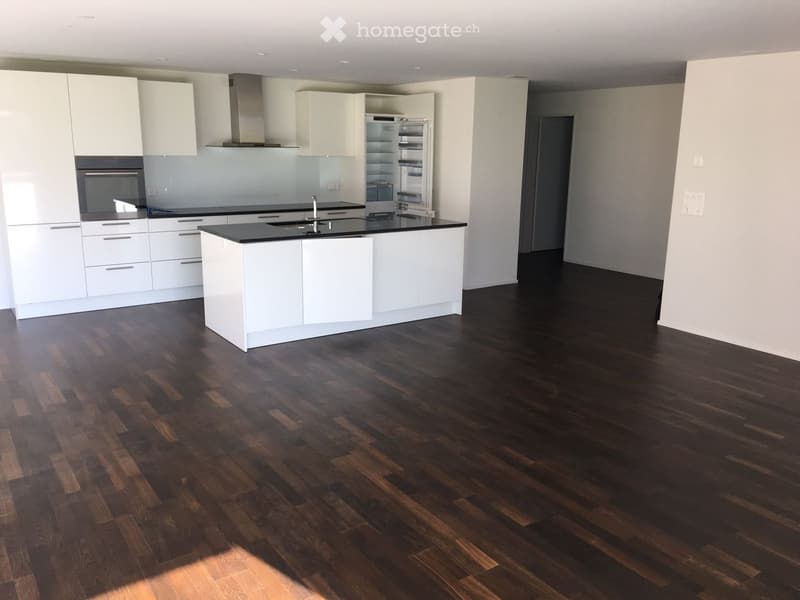 Modern kitchen with white cabinets, dark wooden flooring, central island, and stainless steel appliances including a refrigerator, oven, and sink.