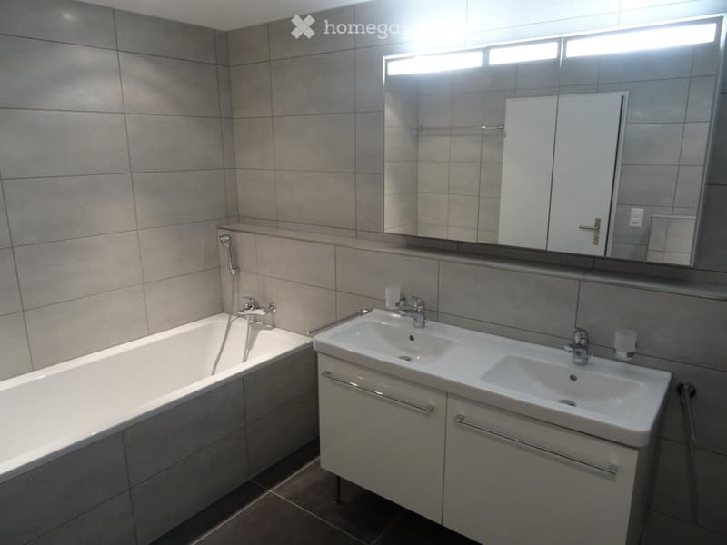 Modern bathroom with bathtub, vanity with double sinks, and large mirror.