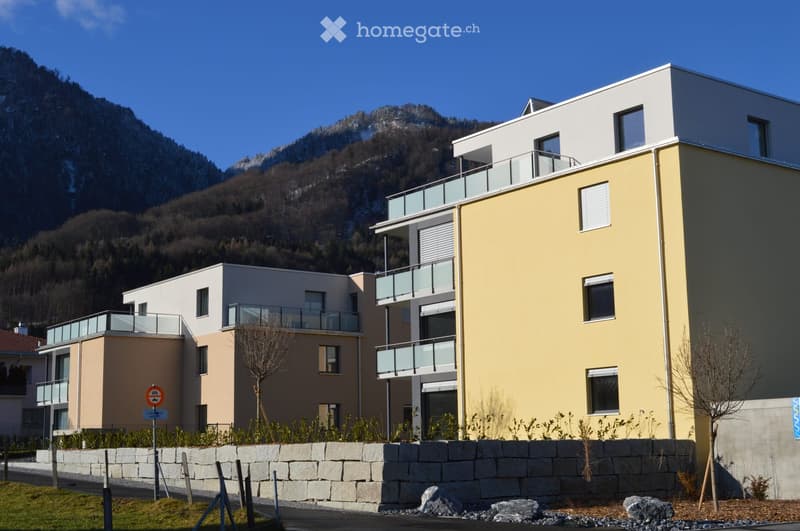 Modern apartment building with multiple terraces and balconies overlooking the mountains.