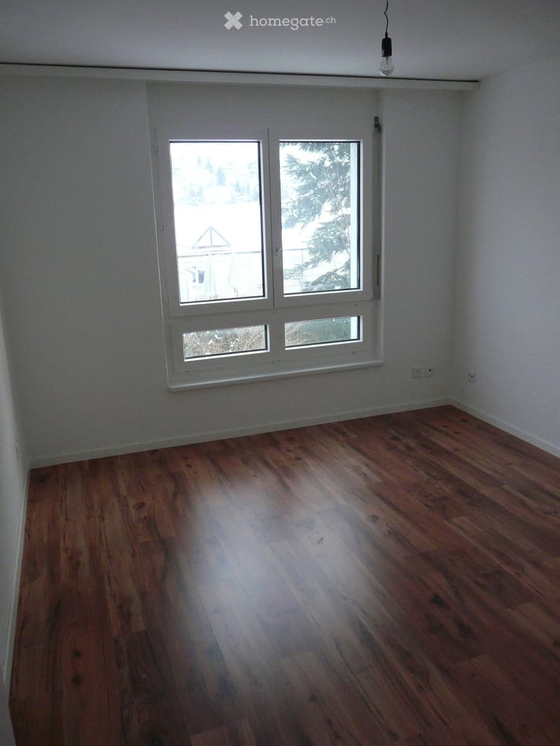 Empty room with wooden flooring and large windows, no furniture or equipment present.