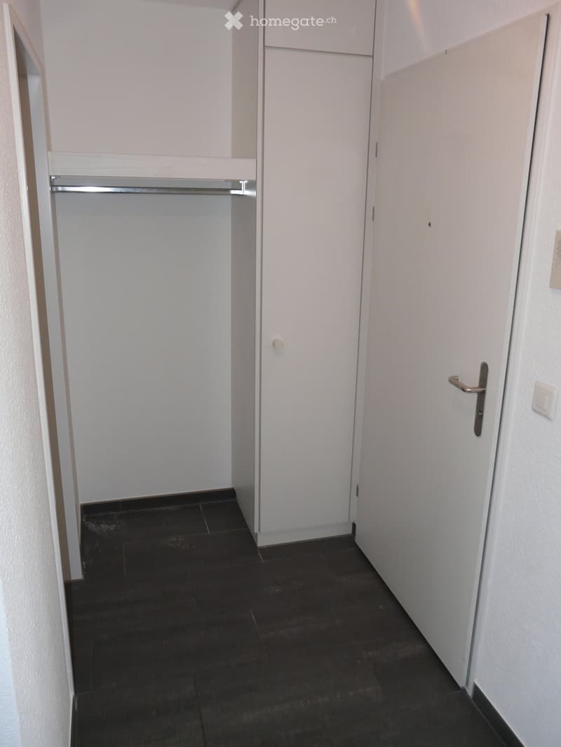 Empty hallway with dark tiled floor, white walls, and two closed doors.