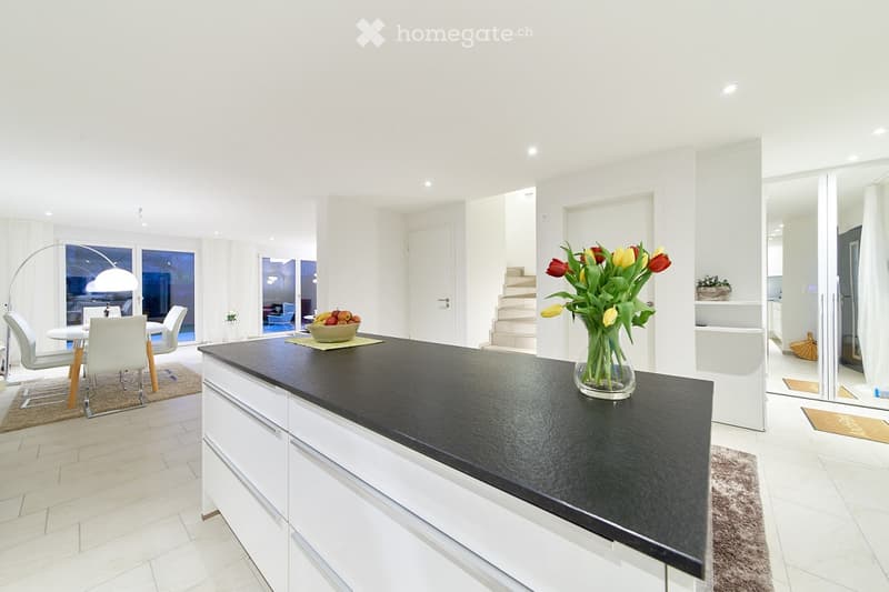 kitchen, black countertops, white cabinets, dining table, windows, stairs, vase of flowers