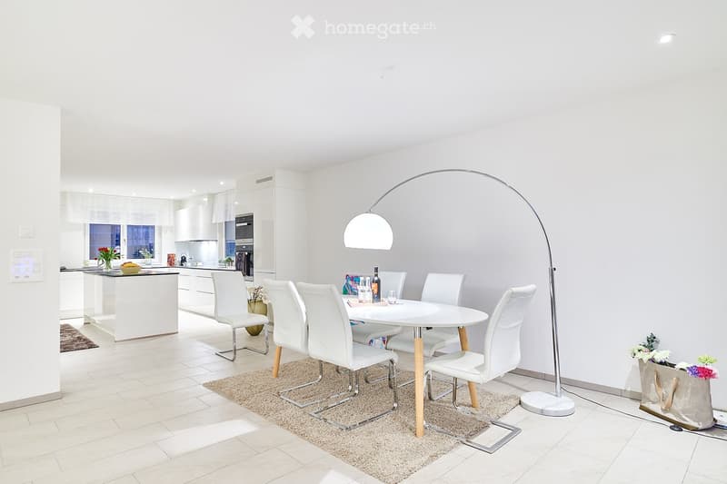 modern dining room with white walls, white table and chairs, floor lamp, rug, kitchen in background