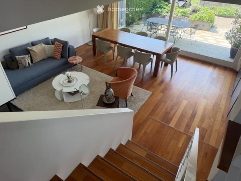 {"visible_features": ["Garden / Outdoor Area"], "type": "Furnished Room", "objects": ["sofa", "coffee table", "dining table", "chairs", "stool", "vase", "floor lamp"], "description": "Open-plan living and dining area with wooden flooring, a grey sofa, a c