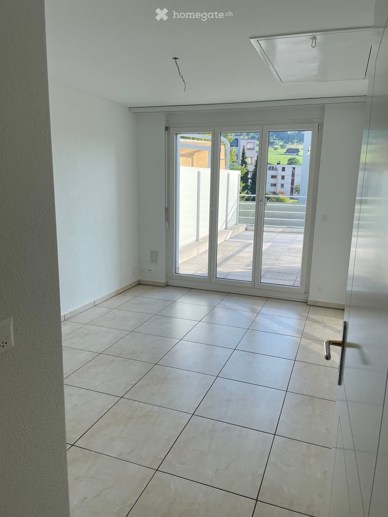 Empty room with tiled floor, white walls, and large sliding glass doors leading to a balcony.