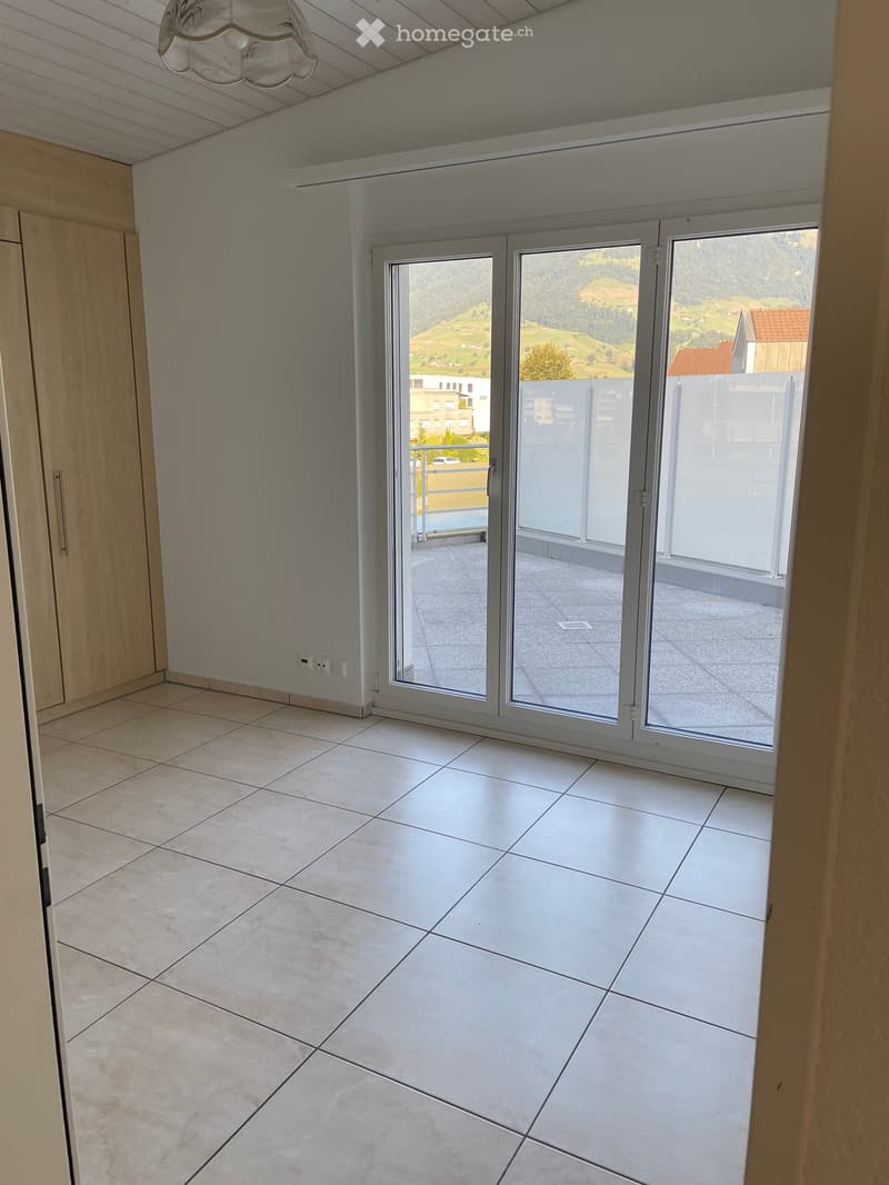 Empty room with tiled floor, large sliding glass doors leading to a balcony with scenic mountain view.