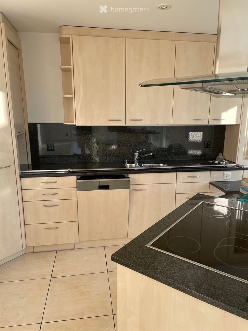 Modern kitchen with light wood cabinets, black granite countertops, stainless steel sink, electric stove, and built-in dishwasher.
