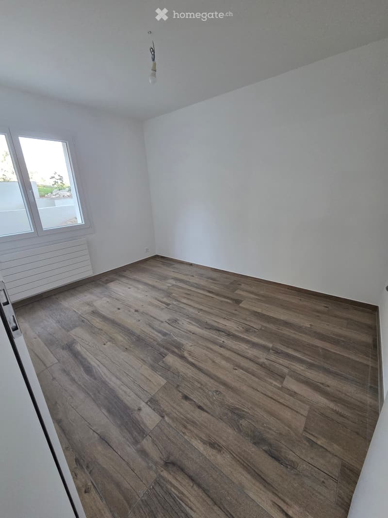 Empty room with wooden flooring, white walls, and a window with a view of the outdoors.