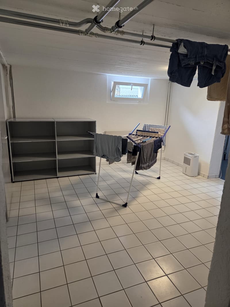Laundry room with tiled floor, metal shelf, clothes drying rack, and air conditioner.