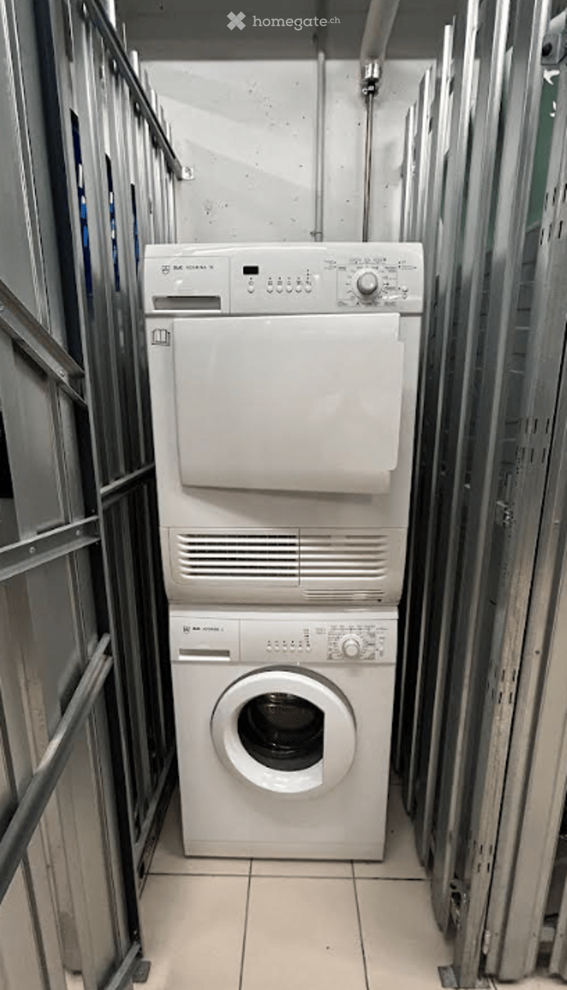 Metal shelving in background, tiled floor, white appliances, stacked washer and dryer