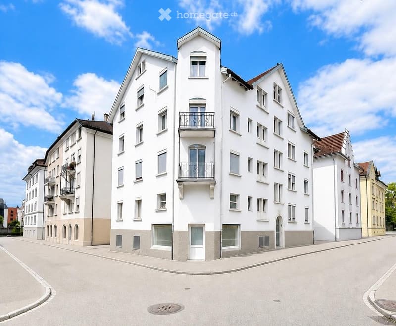 Modern multi-story residential building with white facade, multiple windows, and balconies.