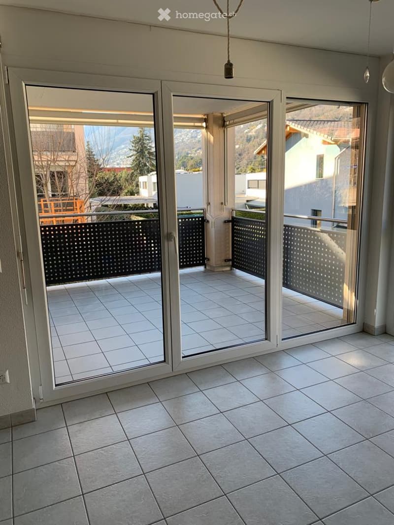 Spacious balcony with tiled flooring, large glass sliding doors, and a scenic mountain view.