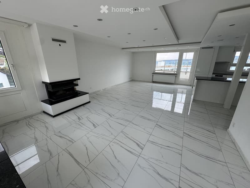 Modern, spacious room with polished marble flooring, white walls, and a built-in fireplace. Large windows offer a view of the cityscape.