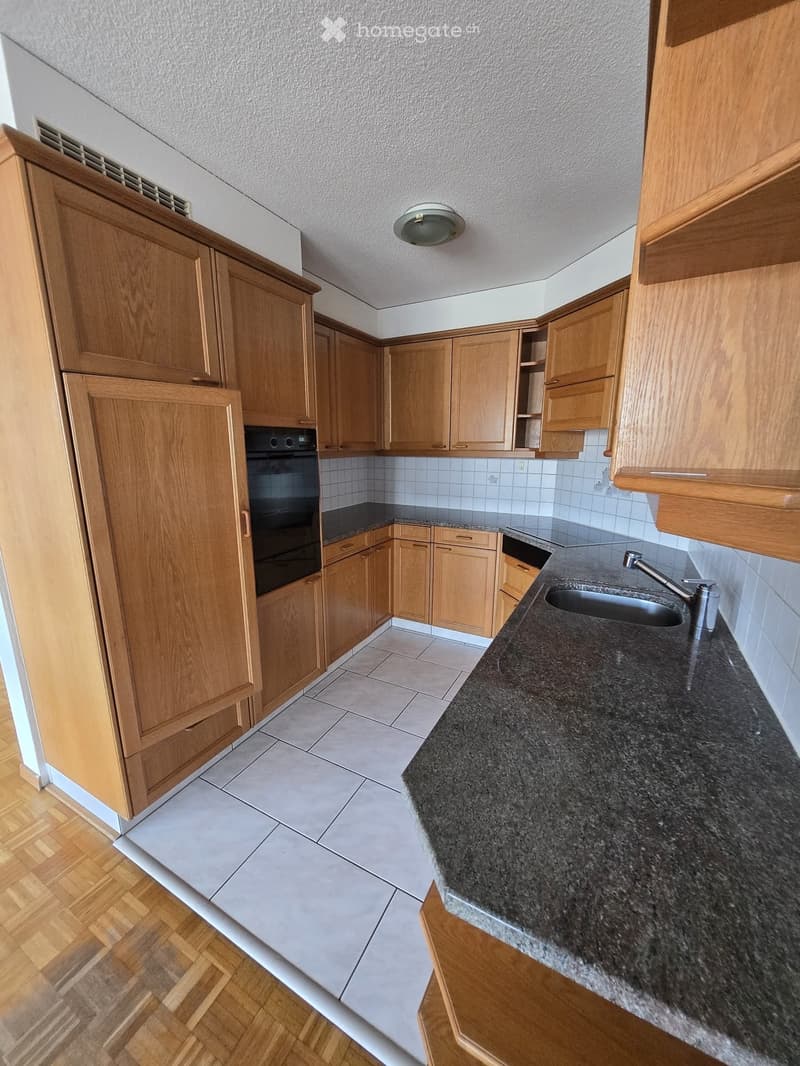 Modern kitchen with wooden cabinets, granite countertop, sink, and built-in oven.