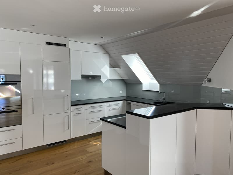 Modern kitchen with white cabinets, black countertops, wooden flooring, and a stainless steel oven.