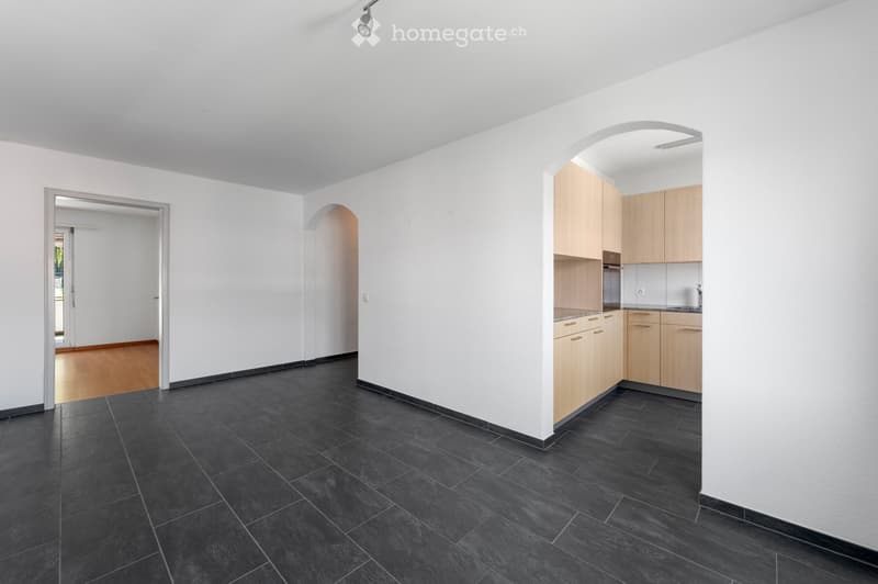 modern design, empty room, tile flooring, white walls, arched doorway, kitchen with cabinets and appliances visible