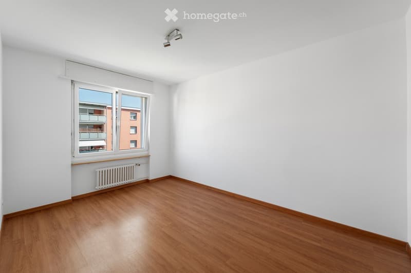 Empty room, white walls, wooden floor, large window, heater, recessed lighting