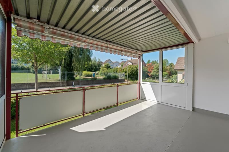 balcony with retractable awning, red railing, panoramic glass window, concrete floor