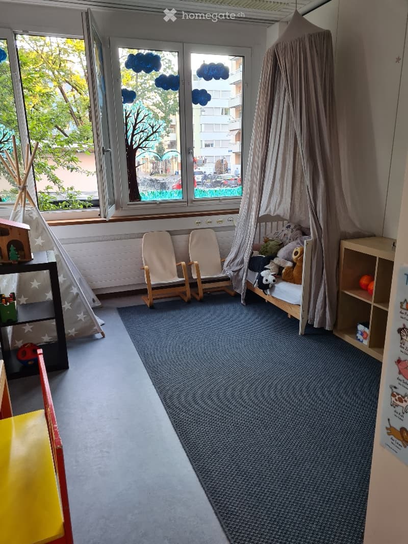 A cozy children's room with a bed under a tent, two wooden chairs, a small shelf with toys, and a colorful play area.