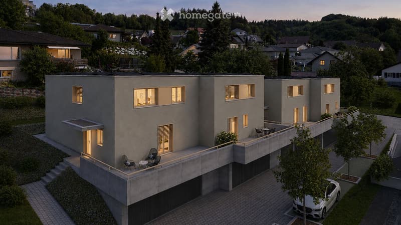 Modern two-story house with grey concrete facade, large windows, raised ground floor, garage, and parking area.