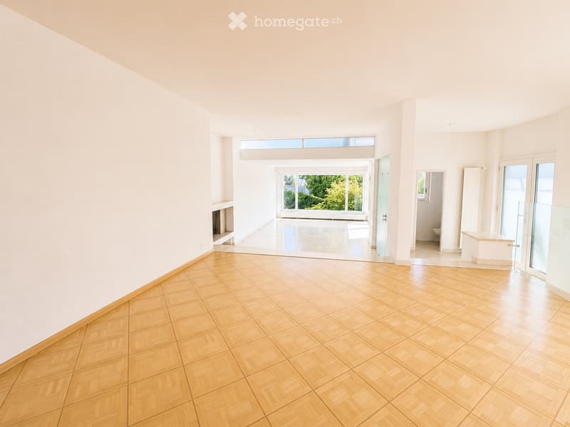 Empty room with wooden herringbone flooring, white walls, large windows, and a fireplace niche. No furniture or equipment present.