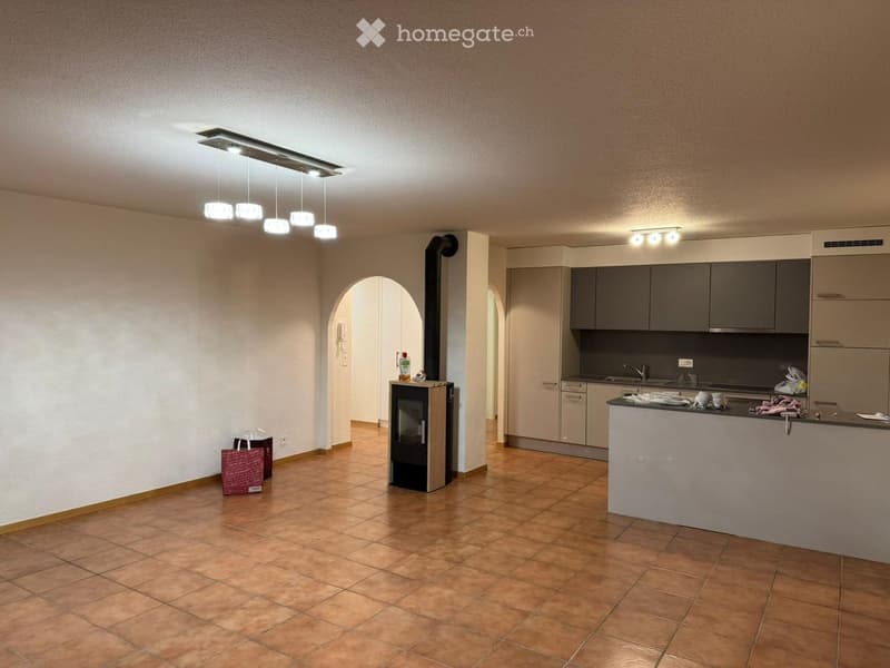Open-plan living and kitchen area with tiled flooring, modern kitchen cabinets, a fireplace, and pendant lighting.