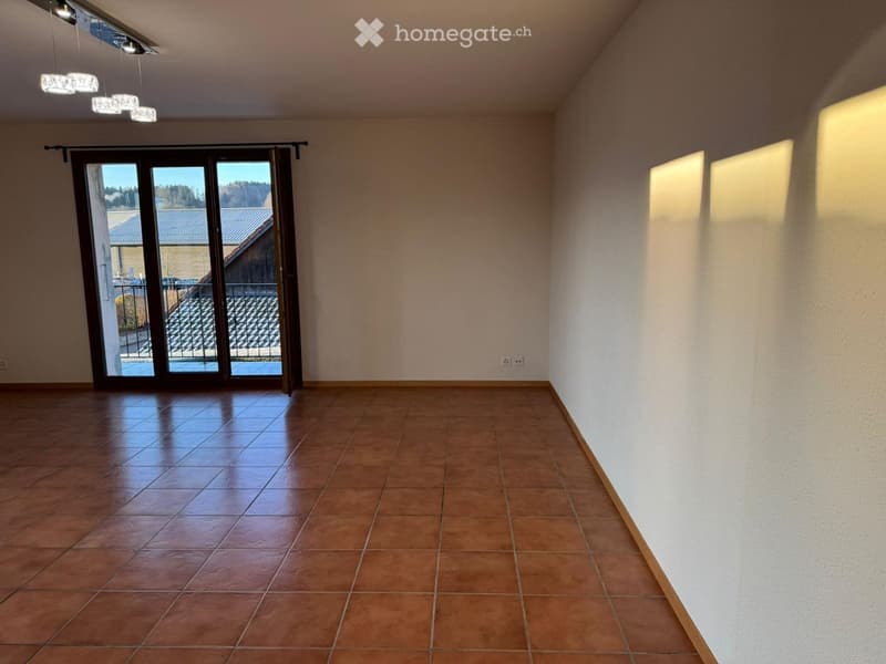 Empty room with tiled floor, large sliding glass door leading to outdoor area, and modern lighting fixture on the ceiling.