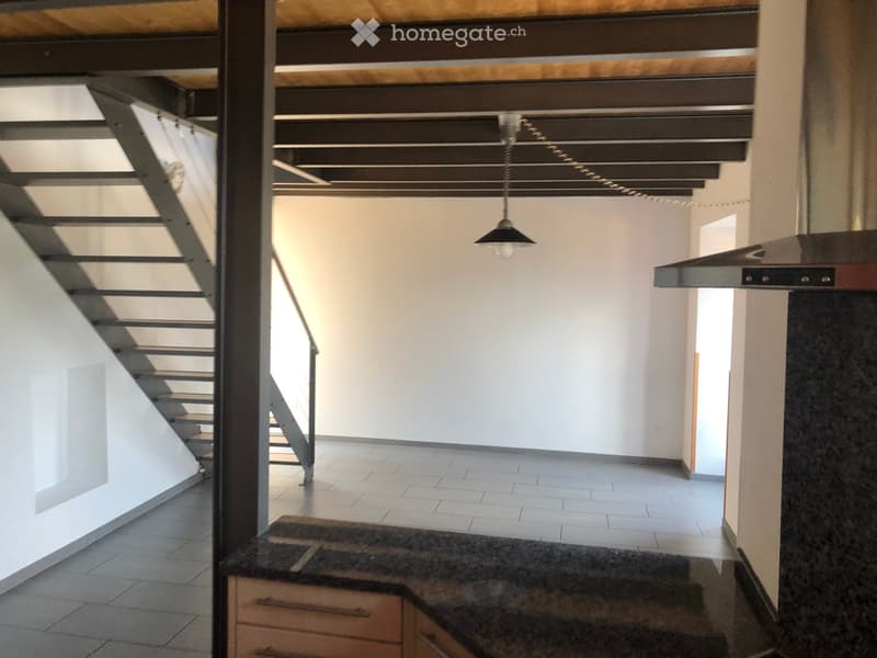 Empty room with tiled floor, white walls, staircase, and modern lighting fixture.