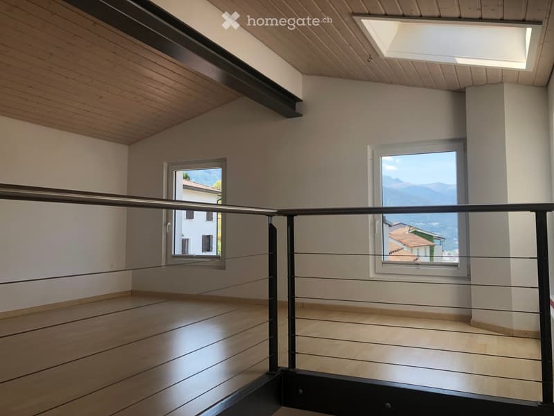 Empty hallway with wooden flooring, white walls, and large windows offering a scenic view of the surrounding area.