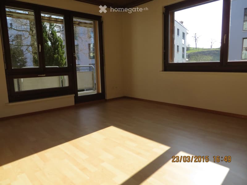 Empty room with wooden flooring, large windows, and natural light. No furniture or equipment present.