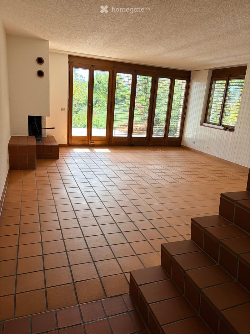 Spacious room with tiled floor, large glass doors leading outside, built-in bench seating, and a fireplace.