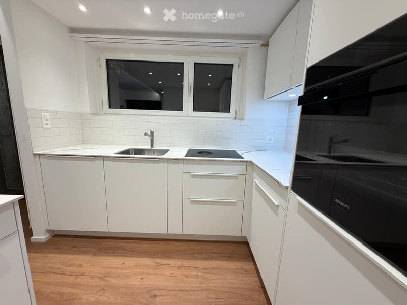 Modern kitchen with white cabinets, wooden flooring, a sink with a faucet, and a built-in oven.