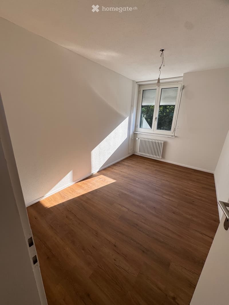 Empty room with wooden flooring, white walls, and a window with blinds. No furniture or equipment is present.