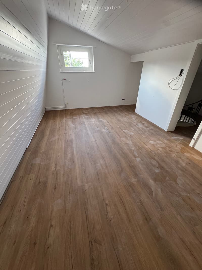 Empty room with wooden flooring, white walls, and a window letting in natural light. No furniture or equipment is present.