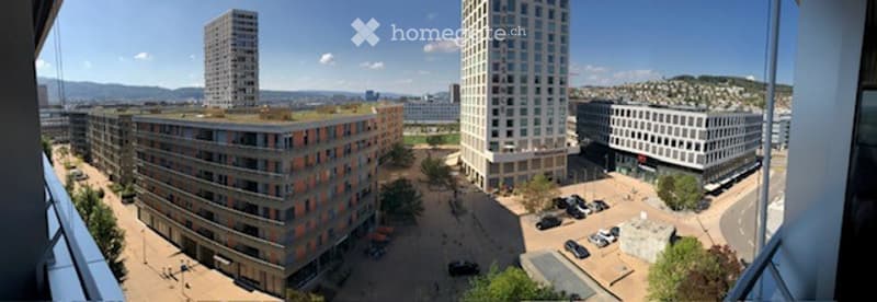 A modern urban complex with multiple high-rise buildings, green spaces, and parking areas.