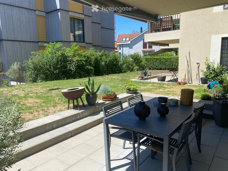 Garden area with a patio, dining table, chairs, vases, and potted plants.