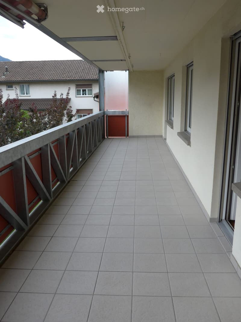 Balcony with tiled floor, metal railing, and access door to the building.