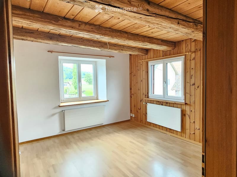 empty room with wooden ceiling and walls, 2 windows with view, radiators