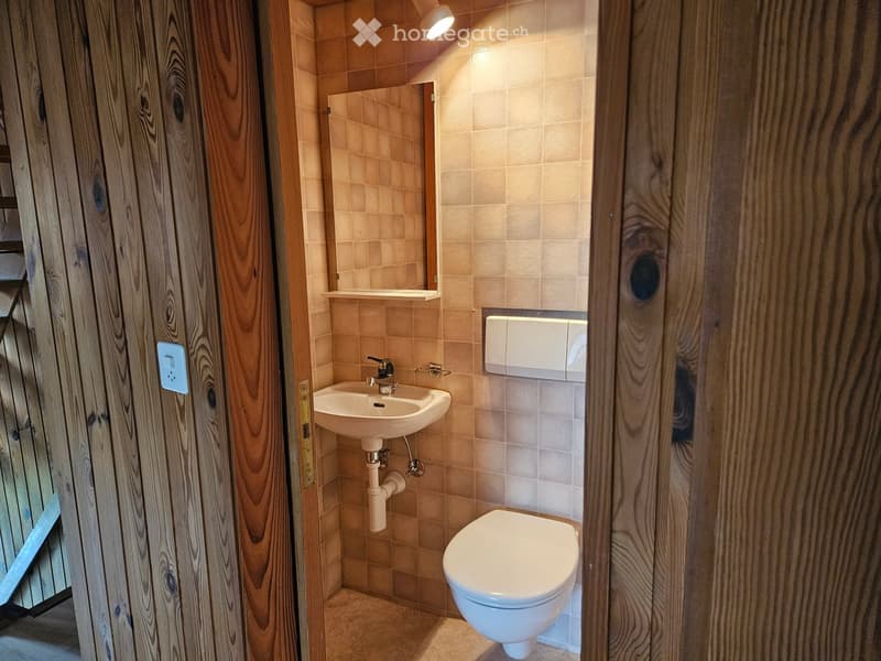 Small bathroom with toilet, sink, mirror, and white tiled walls