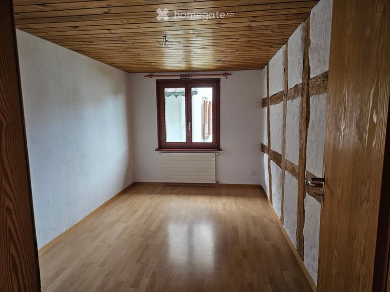 empty room with wooden floor, white walls, large window, wooden door, white radiator