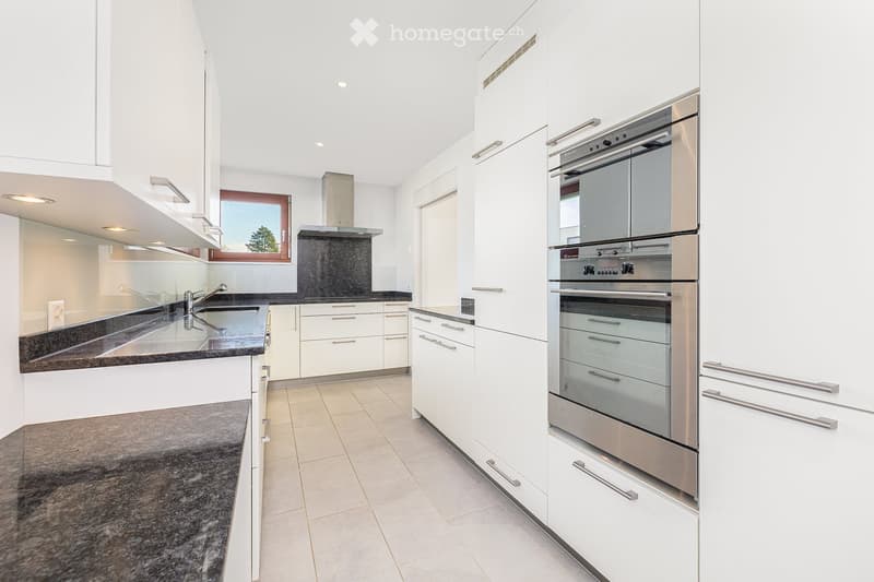 Modern kitchen with white cabinets, granite countertops, stainless steel appliances, and a window with a view.