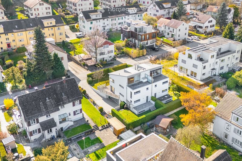 Aerial view of a residential area with multiple houses, driveways, and greenery.