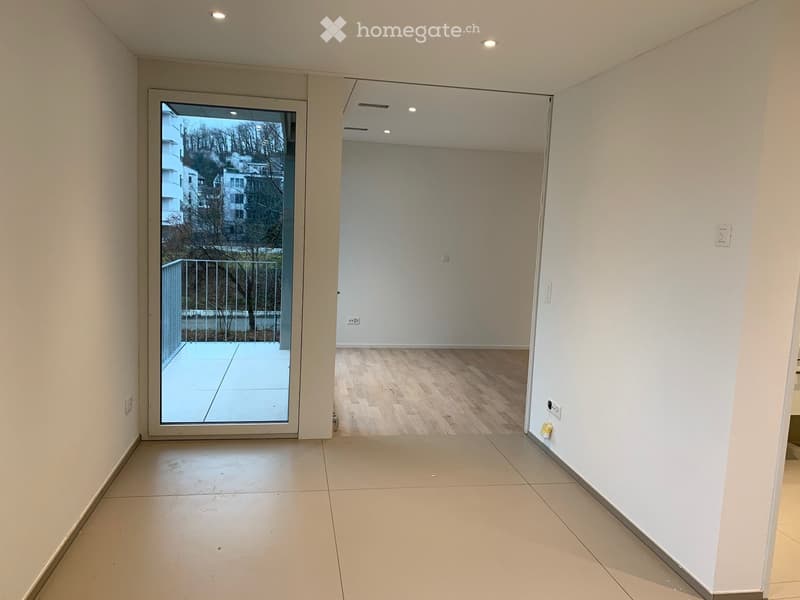 Empty room with tiled floor, white walls, glass door leading to balcony, no furniture