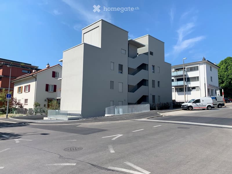 Raised ground floor, concrete, white, large windows, green awnings, small garden area