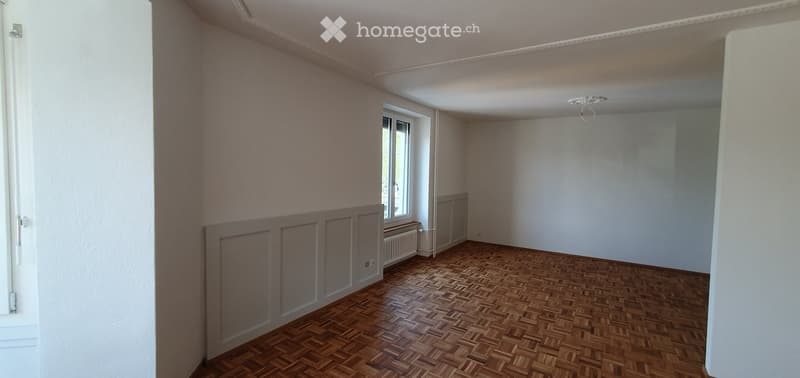 Empty room with wooden parquet flooring, white walls, and a single window with a radiator below it. No furniture or equipment is present.