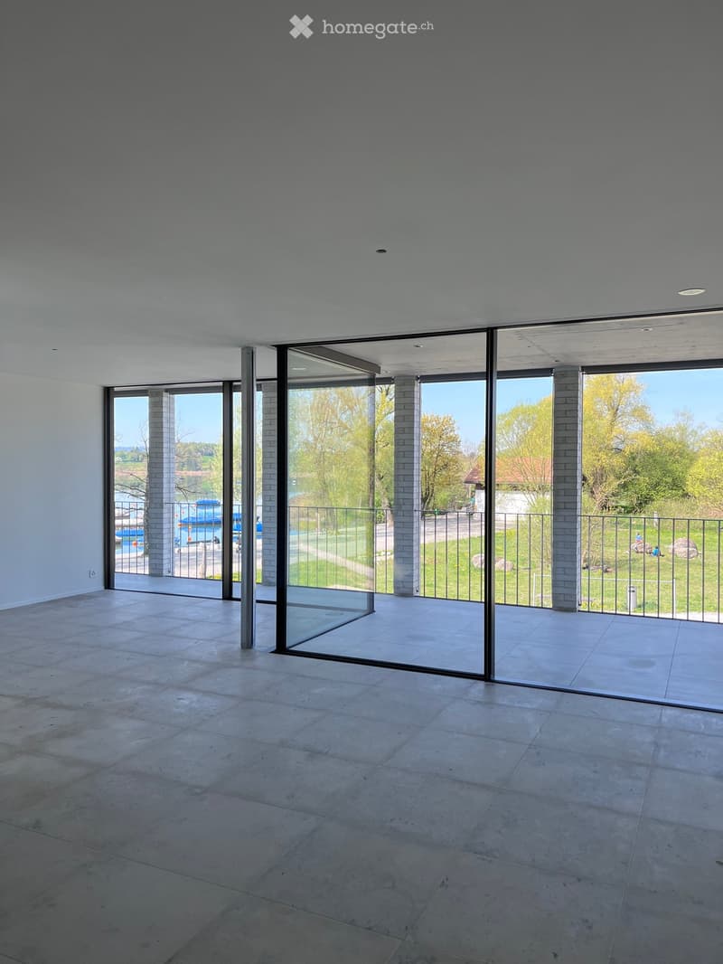 Empty room with large glass sliding doors leading to a balcony, tiled floor, and white walls.