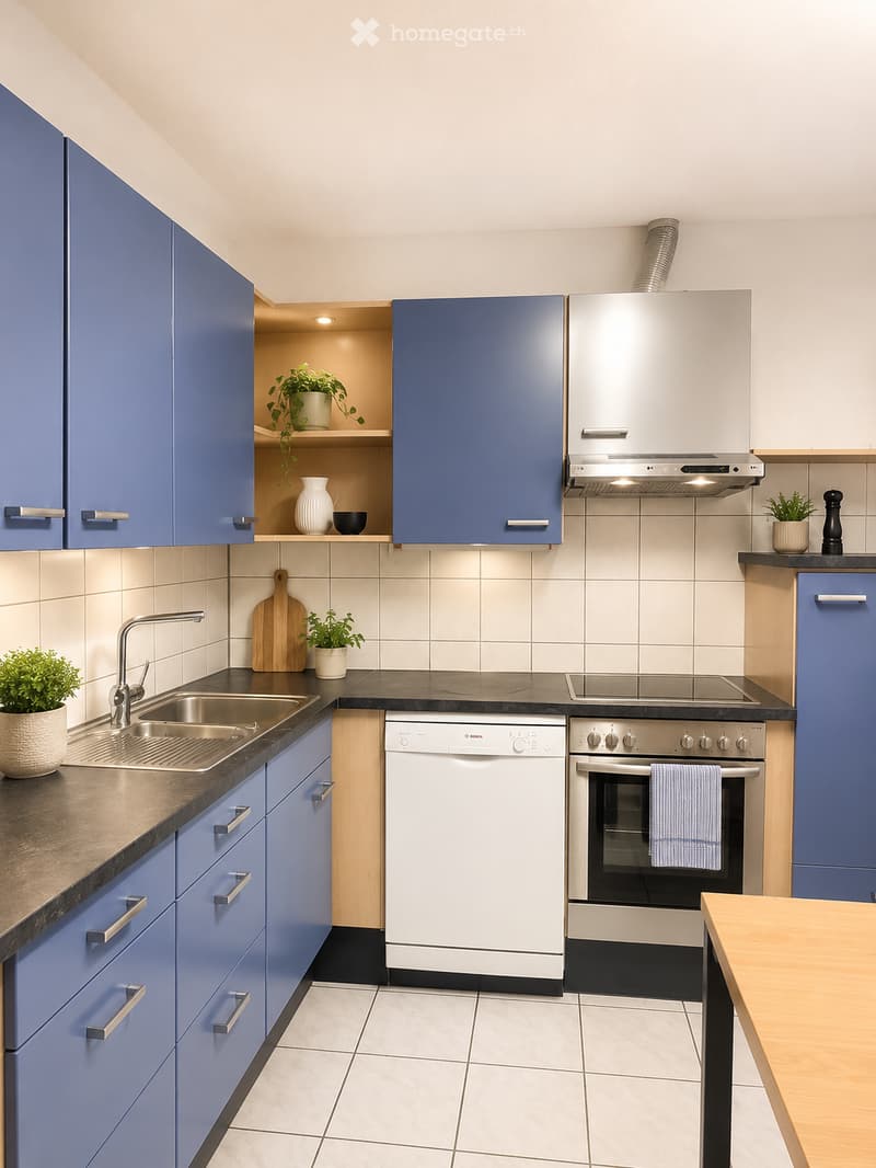Modern kitchen with blue cabinets, stainless steel appliances, a sink, dishwasher, oven, and a small table.